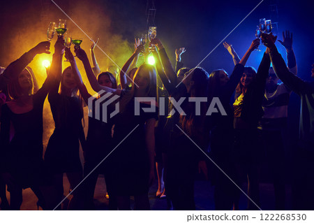 Holidays celebration. Young people attending nightclub, party, cheerfully dancing under neon lights, having fun and relaxing. Holidays celebration. Young people attending nightclub, party, cheerfully dancing under neon lights, having fun and relaxing. 122268530