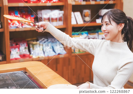 A young woman trying out hand-baked rice crackers [Photo courtesy of Niigata Rice Crackers premium SENBEI DEN] 122268867