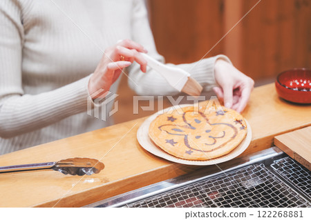 A young woman trying out hand-baked rice crackers [Photo courtesy of Niigata Rice Crackers premium SENBEI DEN] 122268881