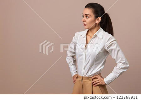 surprised Caucasian businesswoman lady in white shirt and beige pants looing at the side, copy space 122268911