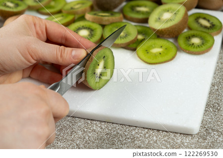 The process of cutting fresh ripe kiwi into slices with a knife. 122269530