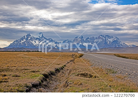 Vast grassy plains with the iconic Torres del Paine mountains under dramatic cloud formations Vast grassy plains with the iconic Torres del Paine mountains under dramatic cloud formations 122270700