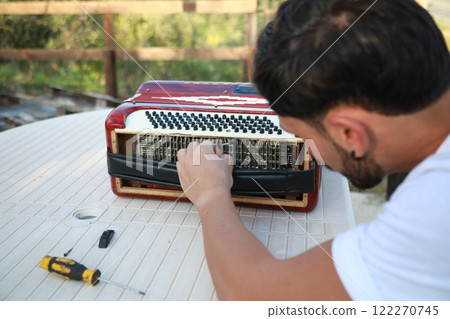 Man Using Tool To Fix And Tune Accordion  122270745