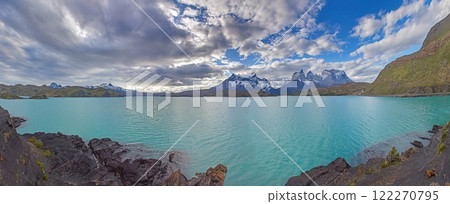 Panoramic view of Lake Pehoe with reflections of dramatic mountains and expansive skies in Torres del Paine 122270795