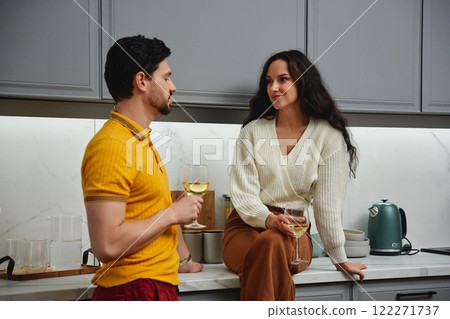 A couple enjoying a relaxed evening with drinks in a modern kitchen A couple enjoying a relaxed evening with drinks in a modern kitchen 122271737