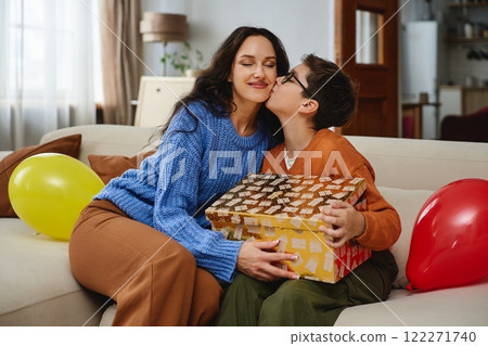 Mother and child celebrating with a gift at home during a joyful moment 122271740