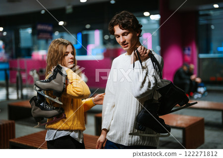 Friends carrying ice skates while enjoying an evening at an ice rink 122271812