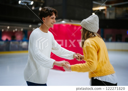 Young couple enjoying ice skating together in a rink during winter Young couple enjoying ice skating together in a rink during winter 122271820