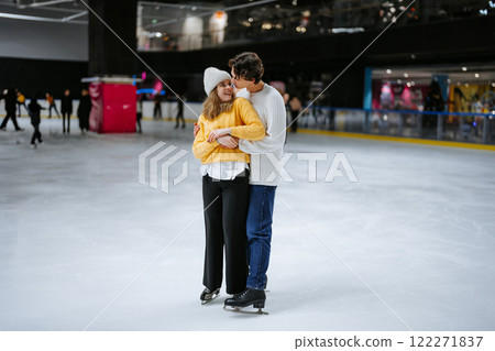 Young couple enjoys ice skating together in a lively indoor rink Young couple enjoys ice skating together in a lively indoor rink 122271837
