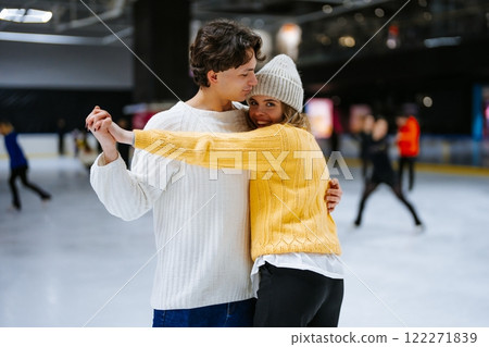 Couple enjoying ice skating together at a rink during winter Couple enjoying ice skating together at a rink during winter 122271839