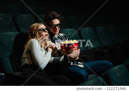 Young couple enjoying popcorn at the movies during a thrilling moment Young couple enjoying popcorn at the movies during a thrilling moment 122271846