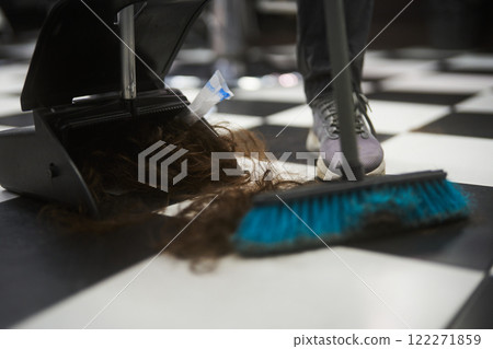 Hair being cleaned up from a black and white checkered floor in a salon 122271859