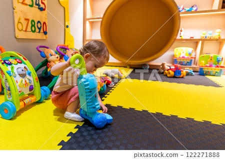 Young child exploring cleaning skills with a toy vacuum cleaner in a colorful and safe playroom for early learning Young child exploring cleaning skills with a toy vacuum cleaner in a colorful and safe playroom for early learning 122271888