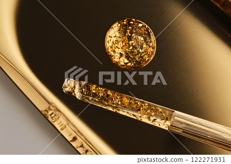 24 k gold facial serum in a pipette on a gold background. 24 k gold facial serum in a pipette on a gold background. 122271931