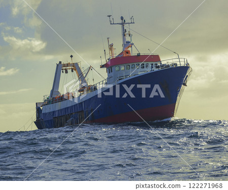 Fishing trawler trawling for fish and seafood in the ocean. Fishing trawler trawling for fish and seafood in the ocean. 122271968