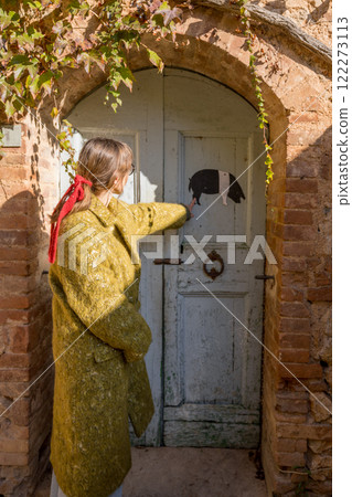 Woman Knocking on Rustic Blue Door 122273113