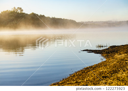 Morning fog over autumn lake water Morning fog over autumn lake water 122273923