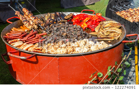 Frying pan with fried potatoes, sausages, meat, mushrooms and pepper. Street food and outdoor cooking concept 122274091
