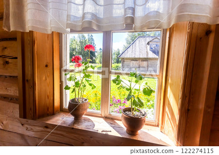 Geranium flowers in ceramic pots on the window of old rural wooden house in sunny day Geranium flowers in ceramic pots on the window of old rural wooden house in sunny day 122274115