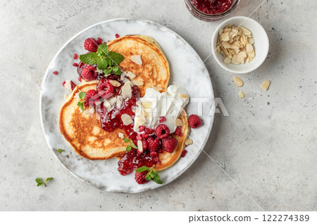 Homemade pancakes with yoghurt, berries and raspberry jam. Maslenitsa or Pancake day breakfast on gray background, top view 122274389
