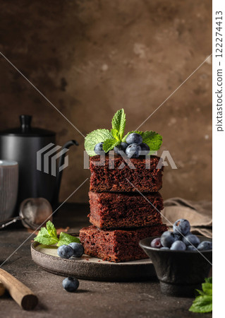 Chocolate brownie cake in stack with berries and mint on top. Homemade sweet chocolate dessert on dark brown background, copy space Chocolate brownie cake in stack with berries and mint on top. Homemade sweet chocolate dessert on dark brown background, copy space 122274413