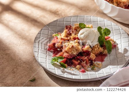 Apple crumble with ice cream on top decorated with mint leaves served in a plate on beige background in natural morning light. Sweet breakfast Apple crumble with ice cream on top decorated with mint leaves served in a plate on beige background in natural morning light. Sweet breakfast 122274426