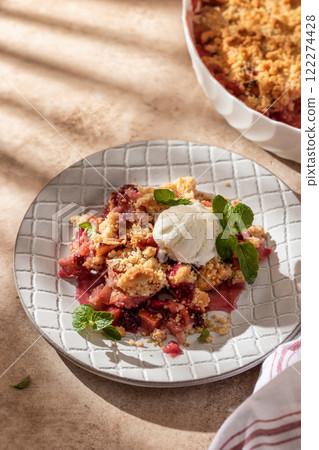 Apple crumble with ice cream on top decorated with mint leaves served in a plate on beige background in natural morning light. Sweet breakfast 122274428