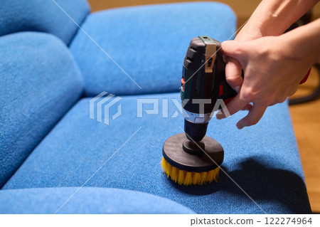 Using a power tool with a brush attachment can effectively clean upholstery furniture and fabrics 122274964