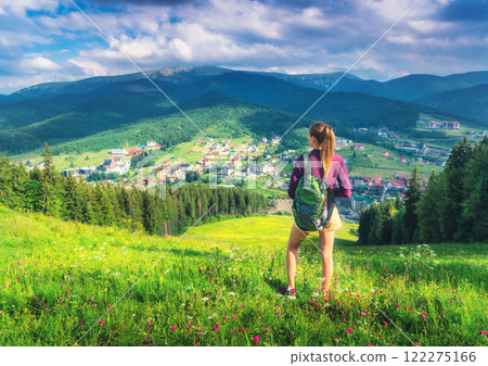 Girl on the hill with yellow flowers and green grass in mountains Girl on the hill with yellow flowers and green grass in mountains 122275166
