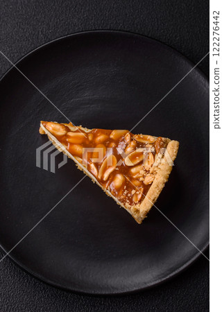 Delicious fresh cheesecake caramel peanut cake with cream and nuts on a ceramic plate on a dark concrete background Delicious fresh cheesecake caramel peanut cake with cream and nuts on a ceramic plate on a dark concrete background 122276442