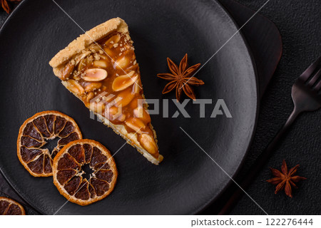 Delicious fresh cheesecake caramel peanut cake with cream and nuts on a ceramic plate on a dark concrete background Delicious fresh cheesecake caramel peanut cake with cream and nuts on a ceramic plate on a dark concrete background 122276444