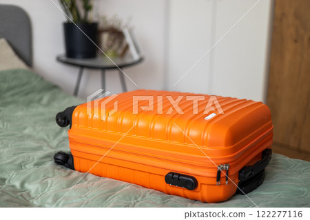 Big orange suitcase on the bed in light room. Baggage case packing getting ready to travel trip vacation. Lifestyle, adventure and tourism concept. Big orange suitcase on the bed in light room. Baggage case packing getting ready to travel trip vacation. Lifestyle, adventure and tourism concept. 122277116