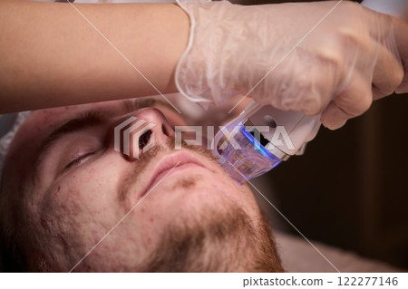 A man is currently undergoing a specialized facial treatment within a serene spa setting 122277146
