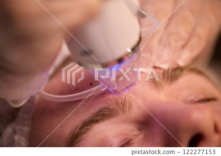 A man is currently undergoing a specialized facial treatment within a serene spa setting A man is currently undergoing a specialized facial treatment within a serene spa setting 122277153