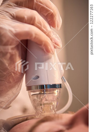 A man is currently undergoing a specialized facial treatment within a serene spa setting A man is currently undergoing a specialized facial treatment within a serene spa setting 122277163