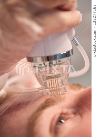 A man is currently undergoing a specialized facial treatment within a serene spa setting A man is currently undergoing a specialized facial treatment within a serene spa setting 122277165