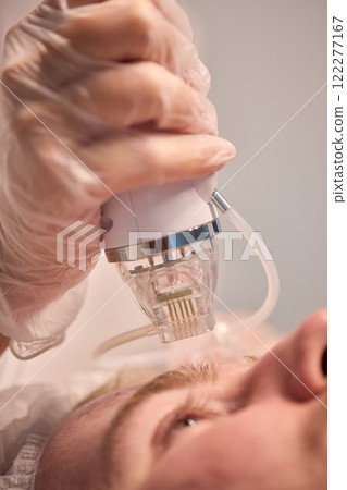 A man is currently undergoing a specialized facial treatment within a serene spa setting 122277167