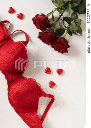 Valentine's day romantic sensual concept. Red lace lingerie, bustier underwear, candy sweets and red roses on white background. View from above. Valentine's day romantic sensual concept. Red lace lingerie, bustier underwear, candy sweets and red roses on white background. View from above. 122277249