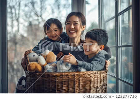 A woman and two children sit in a laundry basket of stuffed animals 122277730