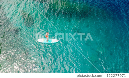 Guy with a paddle standing on a surfboard, aerial view. Active leisure, sports in the sea. Vacation 122277971