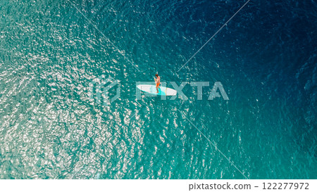 Guy with a paddle standing on a surfboard, aerial view. Active leisure, sports in the sea. Vacation 122277972