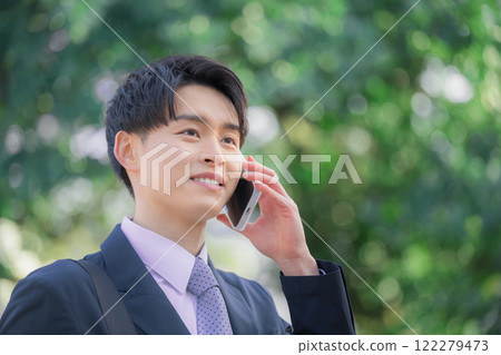 一位 20 多歲的年輕商人在戶外用智慧型手機交談 122279473