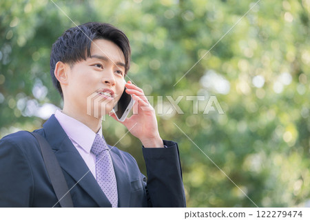 一位 20 多歲的年輕商人在戶外用智慧型手機交談 122279474