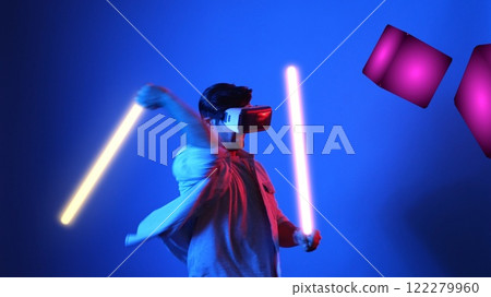 Gamer playing game while holding neon sword and wearing VR glasses. Apparatus. Gamer playing game while holding neon sword and wearing VR glasses. Apparatus. 122279960