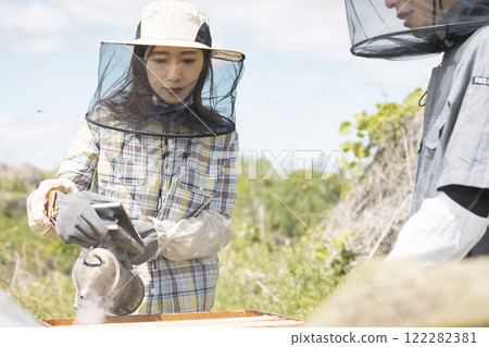 Beekeeping image: A woman using a smoker 122282381