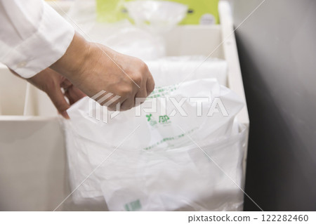 一名女兼職員工在超市收銀台拿塑膠袋 122282460