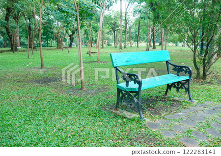 vibrant blue bench sits in lush green park surrounded by trees, inviting relaxation and tranquility. serene atmosphere enhances beauty of nature 122283141