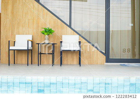 Modern outdoor seating area with two chairs and table by pool Modern outdoor seating area with two chairs and table by pool 122283412