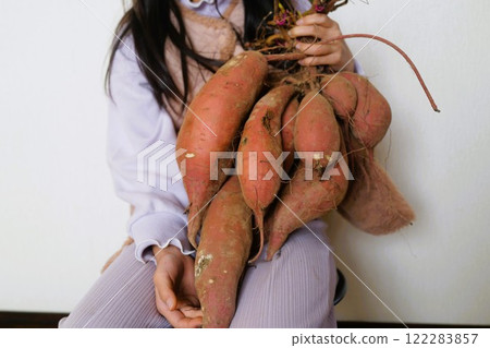一個女孩拿著豐收的紅薯 122283857