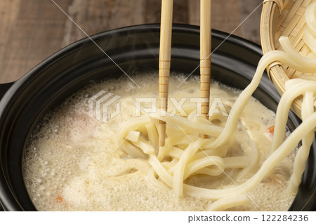 To finish off the hot pot, add udon noodles and spring onions to the pot and simmer. 122284236